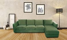 a green couch sitting on top of a hard wood floor next to two framed pictures