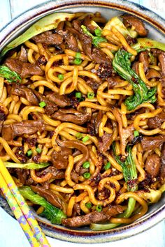 beef and noodles in a bowl with chopsticks