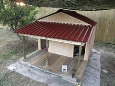 a small wooden structure with a red tin roof