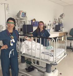 two women in scrubs standing next to a hospital bed