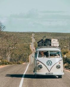 the vw bus is driving down the road with luggage on it's roof