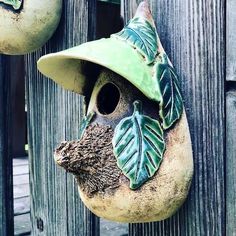 a bird house with a hat on it's head hanging from a wooden fence