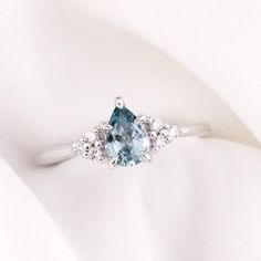 a blue and white diamond ring sitting on top of a white cloth