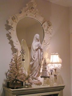 a white statue sitting on top of a table next to a mirror and christmas decorations