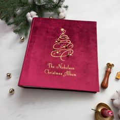 a red christmas album sitting on top of a white table next to ornaments and decorations