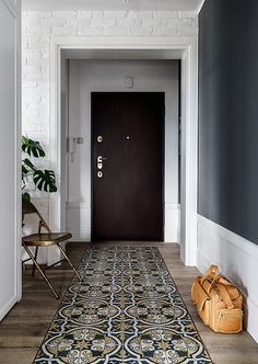 a black and white hallway with an ornate rug on the floor next to a wooden door