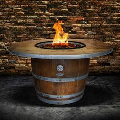 a fire pit sitting on top of a barrel in front of a brick wall and floor