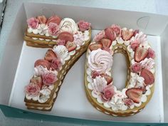 the number seventy is decorated with strawberries and flowers on top of cake in a box