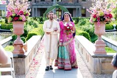 a man and woman standing next to each other in front of a building with flowers