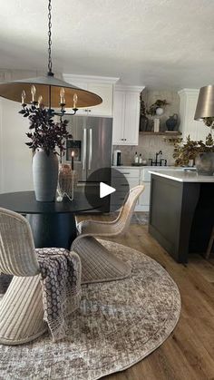 a living room and kitchen area with an oval rug on the floor, chairs around a table