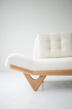 a white couch sitting on top of a wooden frame in front of a white wall