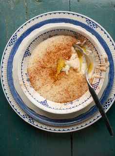 a bowl of food on a blue and white plate with a spoon in the bowl