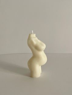 a white candle that is shaped like a pregnant woman's torso on a table