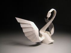 an origami swan sitting on top of a white table next to a black background