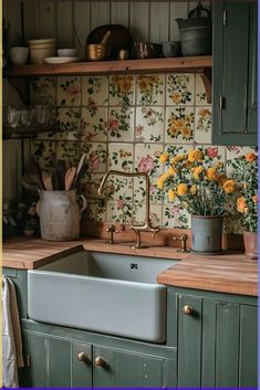 a kitchen with green cabinets and yellow flowers on the counter top, next to a sink