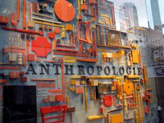 an art exhibit with orange and yellow objects on the wall in front of it that says anthropologie