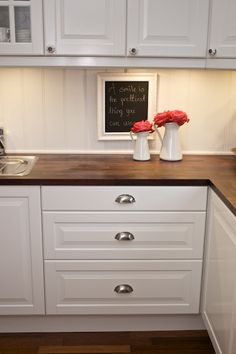 a kitchen with white cabinets and wood counter tops