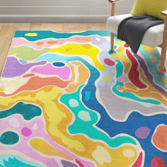 a colorful area rug with an abstract design on the floor in front of a chair