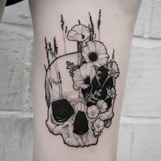 a black and white photo of a skull with flowers on it's side thigh