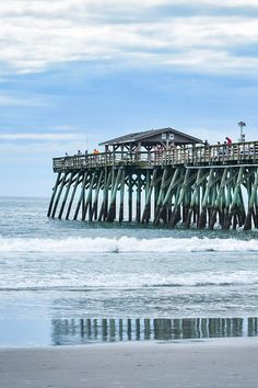 people are standing on the pier at the beach