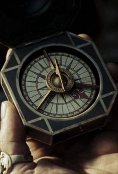 a person holding a small compass in their hand and looking at it with both hands