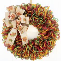 a multicolored wreath hanging on the front door with a bow tie around it