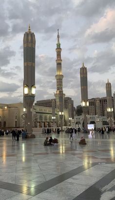 people are sitting on the ground in front of some tall buildings with lights at night