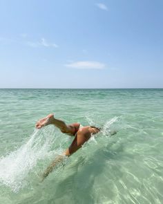 a woman is swimming in the ocean with her legs spread out and head above water