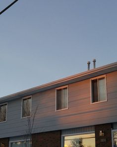 the building has three windows and is lit up at sunset or dawn with no one in sight