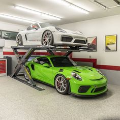 two sports cars are parked on top of each other in a car garage with one being lifted by a scissor