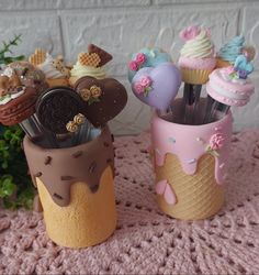 two vases filled with different types of cupcakes on a pink tablecloth