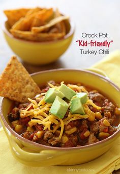 a yellow bowl filled with chili, beans and avocado