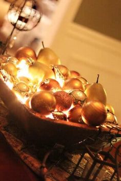 a bowl filled with apples sitting on top of a wooden table next to a lamp