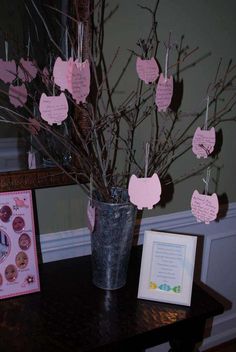 a vase filled with branches covered in pink paper and baby's breath notes hanging from clothes pins