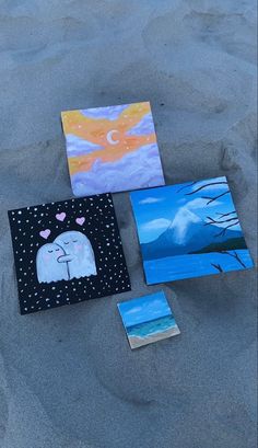 four paintings are laid out on the sand