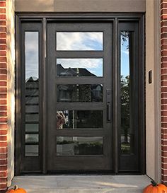 two pumpkins sitting on the front steps of a brick building with a black door