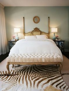 a bedroom with a zebra rug on the floor and a bed in the middle that has a white bedspread