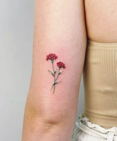 a woman's arm with red flowers tattooed on the left side of her arm