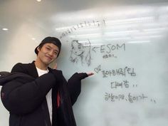 a man standing in front of a whiteboard with writing on it and pointing to the side