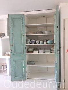 an open cabinet with plates and bowls on it in a room that has white walls