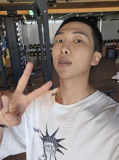 a young man making the vulcan sign with his hand while standing in front of a gym