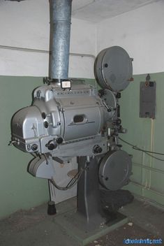 an old machine is sitting in the corner of a room with green walls and pipes