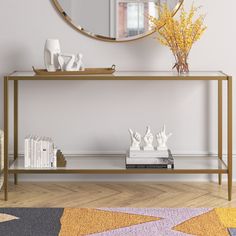 a table with a mirror, vases and books on it in front of a white wall