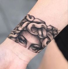 a woman's hand with a tattoo on it that has an image of a snake crawling out of her head