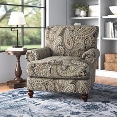 a living room with a chair, lamp and bookshelf in the back ground