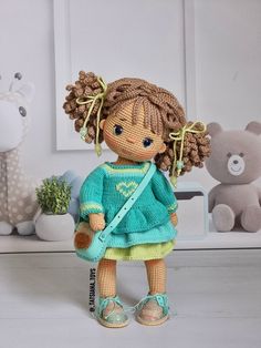 a crocheted doll is standing in front of a teddy bear and other stuffed animals