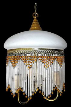 a chandelier hanging from the ceiling with beads and chains on it's sides