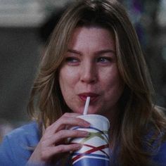 a woman drinking from a cup with a straw in her mouth