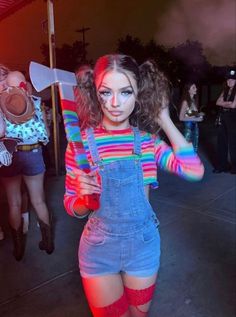 a woman in overalls holding a knife and wearing red knee high socks with rainbow paint on her face