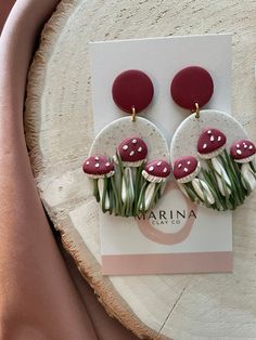 a pair of red and white mushroom earrings on top of a card